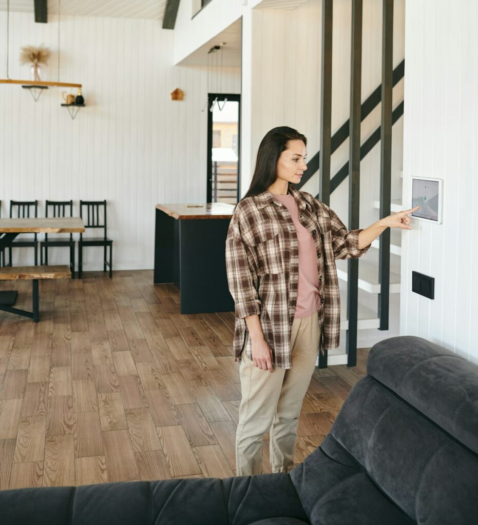 Young woman standing in living-room in front of home security panel